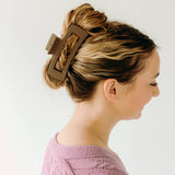 A woman wearing a mocha XL Essential Lilac Clip, a matte hair accessory with a hinge closure. 4.8 inches long, suitable for all hair types.