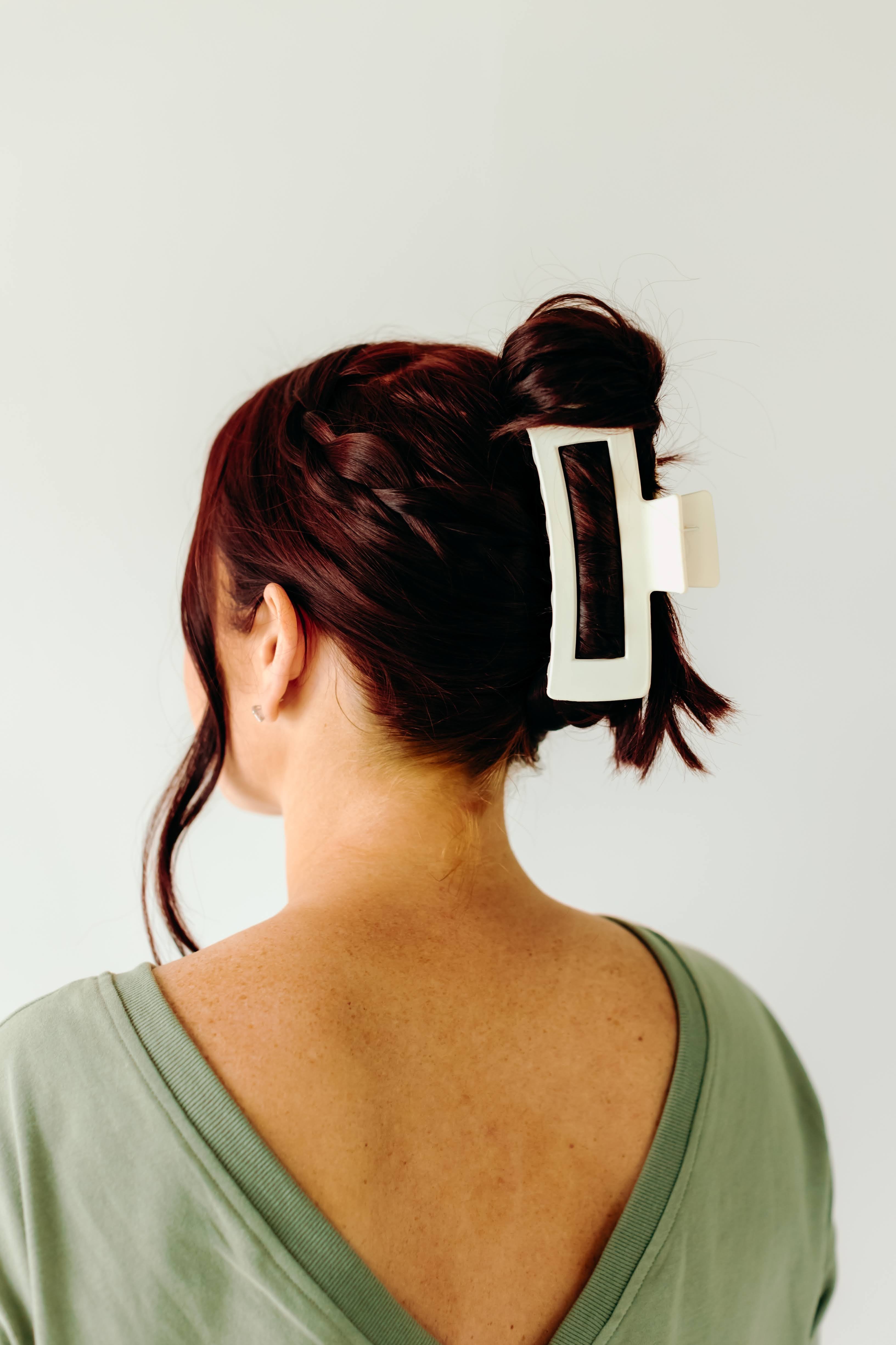 A woman wearing a white XL Essential Lilac Clip, a matte hair accessory with a hinge closure. 4.8 inches long, suitable for all hair types.