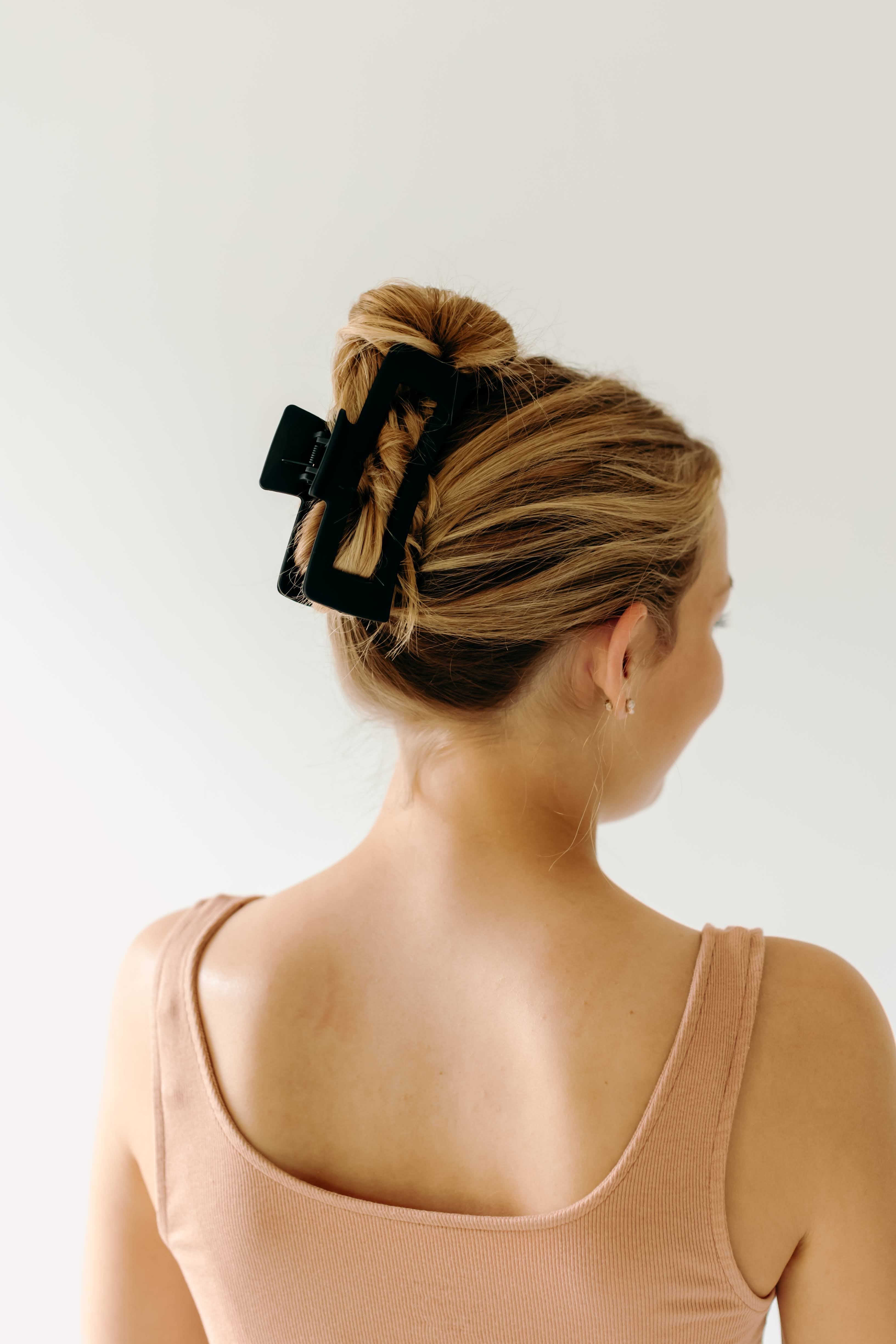 A woman wearing a black XL Essential Lilac Clip, a matte hair accessory with a hinge closure. 4.8 inches long, suitable for all hair types.