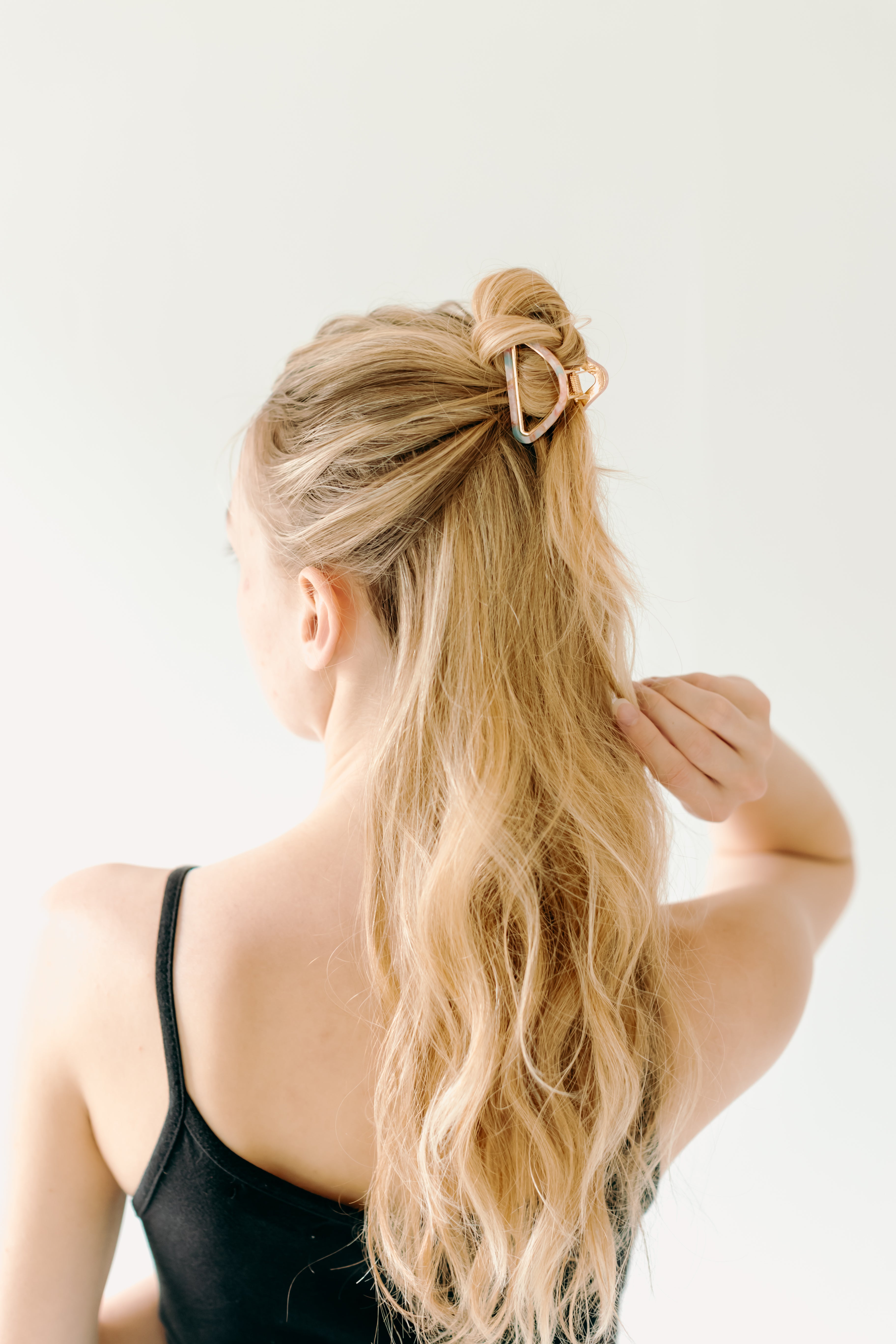 A women with long hair confidently wearing an Endless Weekend Lilac Clip, a glossy metal hair accessory with a hinge closure. Perfect for all hair types.