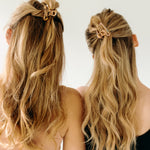 Two women with long hair, each wearing an Endless Weekend Lilac Clip, a glossy metal hair accessory with a hinge closure. Perfect for all hair types.