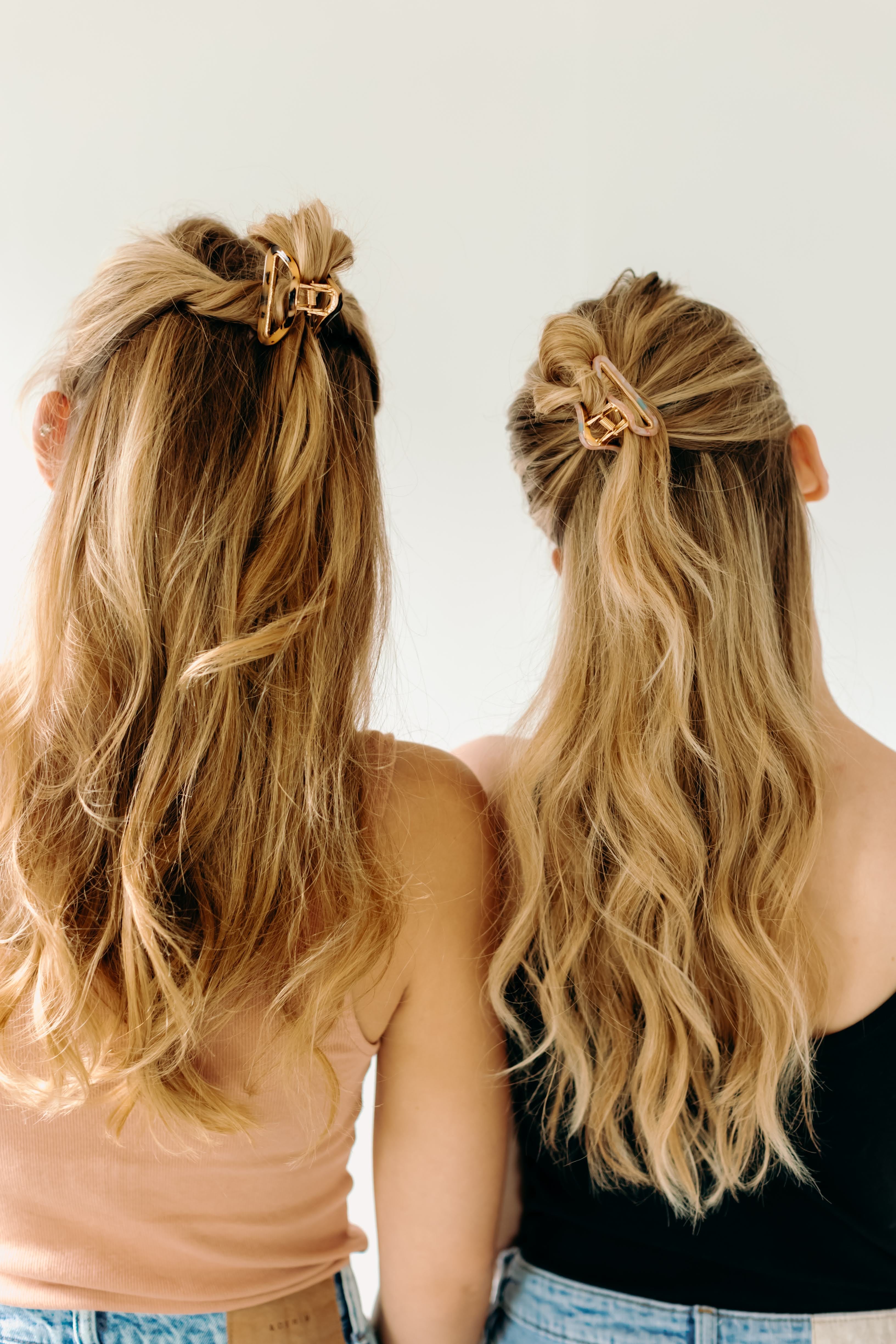 Two women with long hair, each wearing an Endless Weekend Lilac Clip, a glossy metal hair accessory with a hinge closure. Perfect for all hair types.