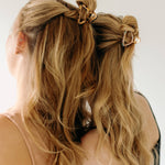 Two women with long hair, each wearing an Endless Weekend Lilac Clip, a glossy metal hair accessory with a hinge closure. Perfect for all hair types.