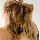 Two women with long hair, each wearing an Endless Weekend Lilac Clip, a glossy metal hair accessory with a hinge closure. Perfect for all hair types.