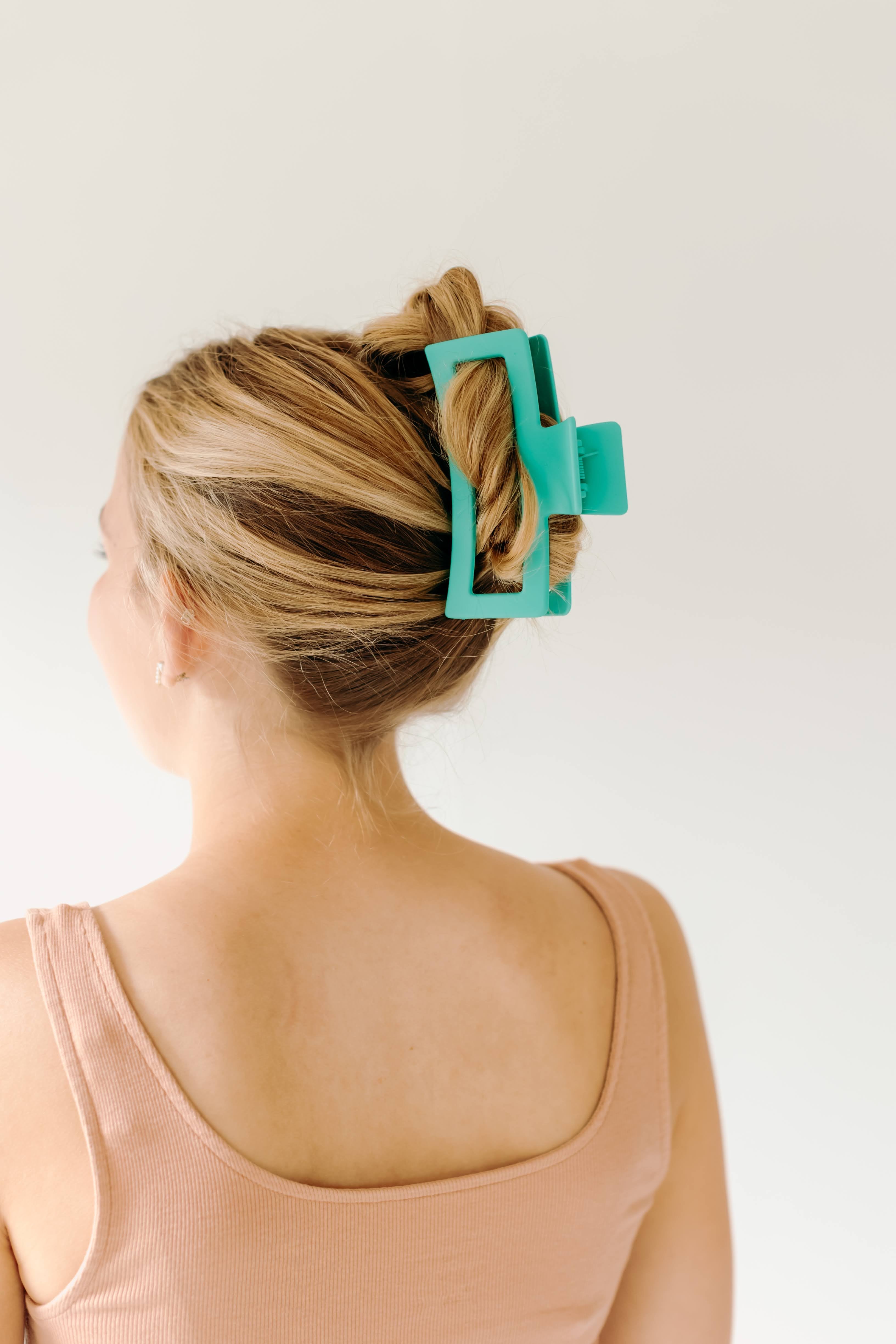 A woman wearing a green Vacation Vibes Lilac Clip in her hair, a fashion accessory perfect for all hair types. Matte material, 4.8 inches long, with a hinge closure.