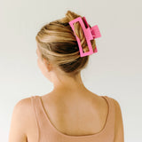 A woman wearing a pink Vacation Vibes Lilac Clip in her hair, a fashion accessory perfect for all hair types. Matte material, 4.8 inches long, with a hinge closure.