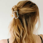 A woman wearing a white Happy Hour Lilac Clip, a glossy hair accessory with a hinge closure. Perfect for all hair types. Size: 1.8 inches long.