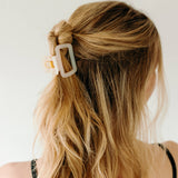 A woman wearing a white Happy Hour Lilac Clip, a glossy hair accessory with a hinge closure. Perfect for all hair types. Size: 1.8 inches long.