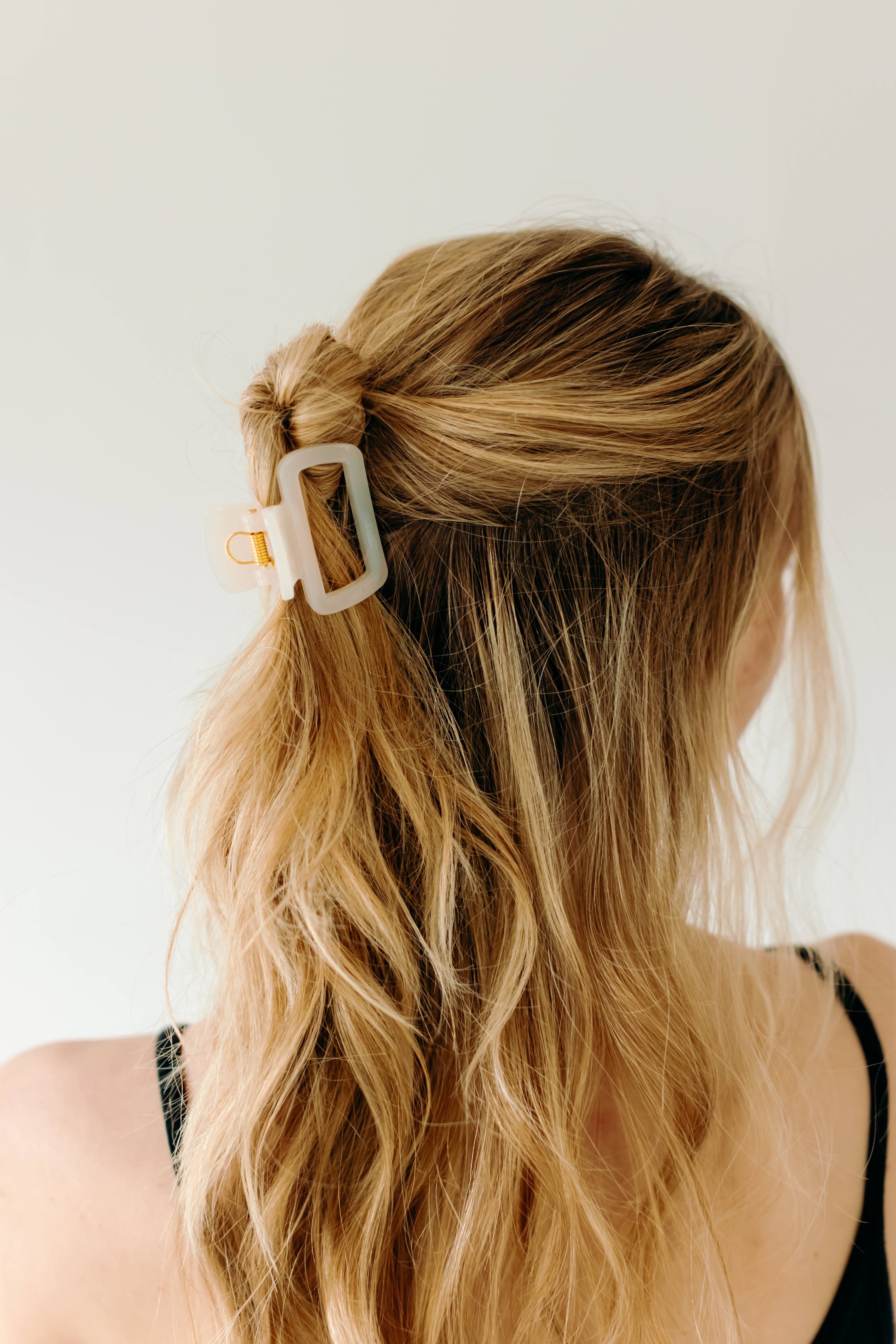 A woman wearing a white Happy Hour Lilac Clip, a glossy hair accessory with a hinge closure. Perfect for all hair types. Size: 1.8 inches long.