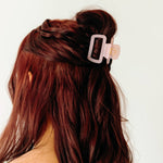 A woman wearing a pink Happy Hour Lilac Clip, a glossy hair accessory with a hinge closure. Perfect for all hair types. Size: 1.8 inches long.