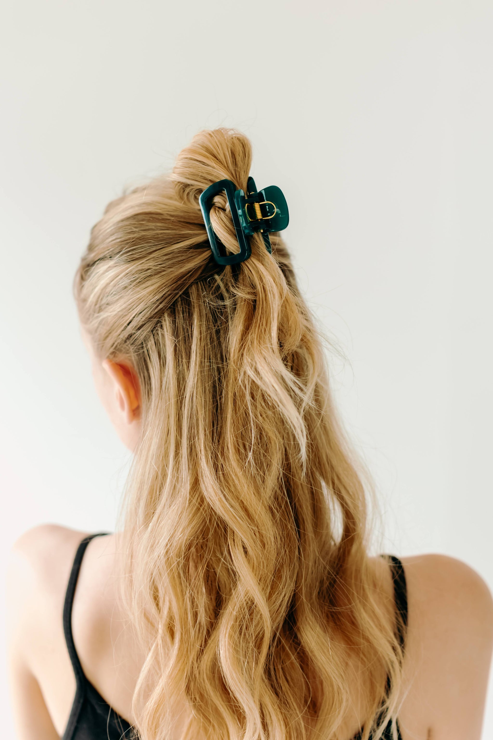 A woman wearing a dark green Happy Hour Lilac Clip, a glossy hair accessory with a hinge closure. Perfect for all hair types. Size: 1.8 inches long.