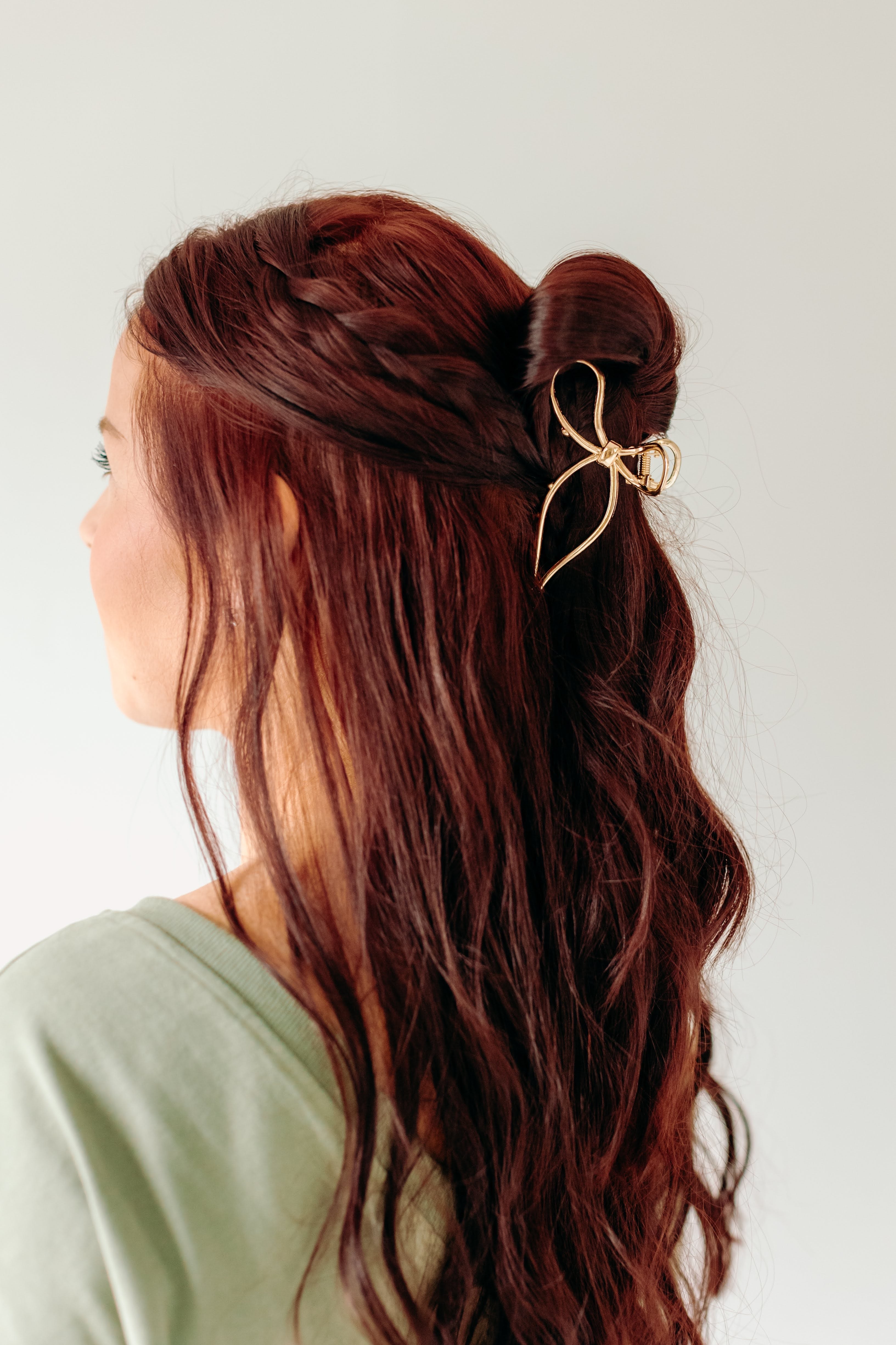 A woman with stylish hair wearing a One in a Million gold hair clip, showcasing the Lilac Clip, a 4.2-inch metal claw clip with a hinge closure for all hair types.