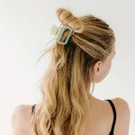 A woman wearing a green Happy Hour Lilac Clip, a glossy hair accessory with a hinge closure. Perfect for all hair types. Size: 1.8 inches long.