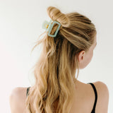 A woman wearing a green Happy Hour Lilac Clip, a glossy hair accessory with a hinge closure. Perfect for all hair types. Size: 1.8 inches long.
