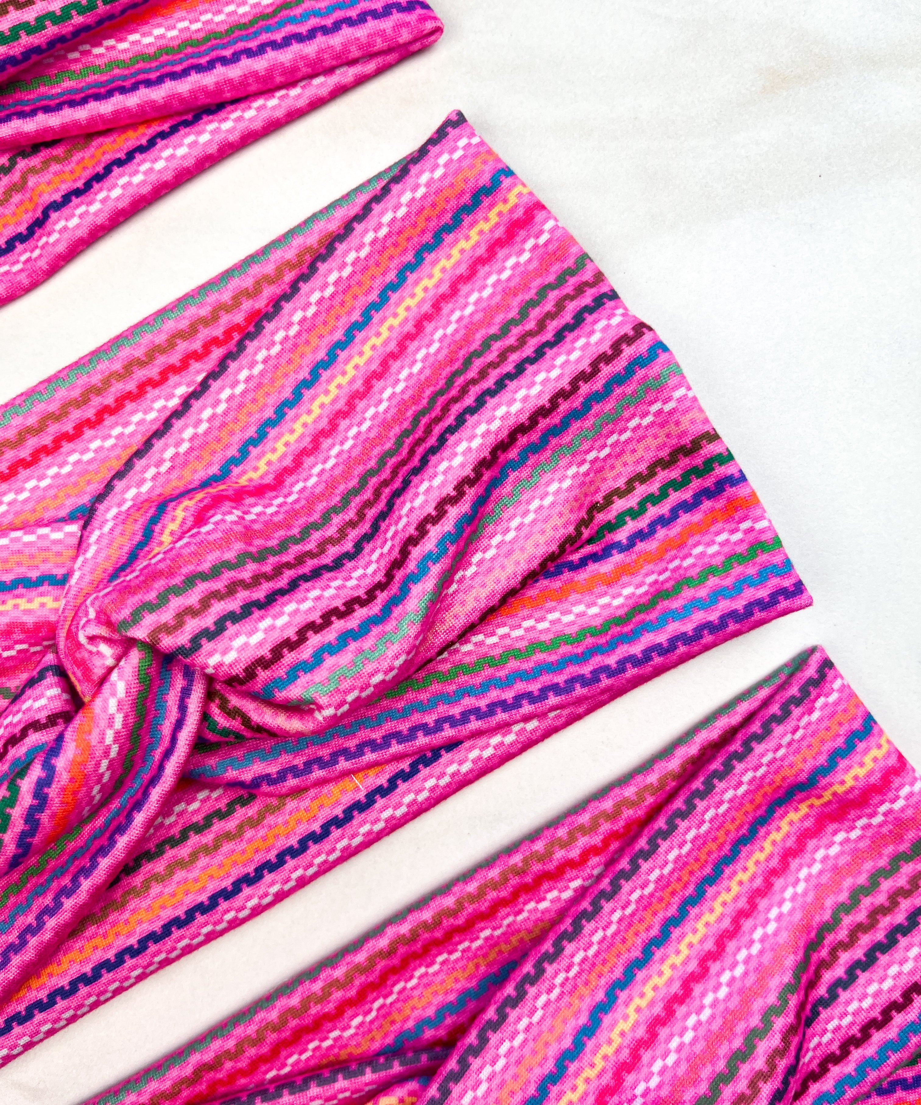 Adult women's fuchsia headband with purple, yellow, green and blue serape stripe pattern