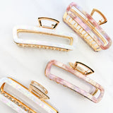 White and pink Break A Leg Clips from The Sarah Wallace Collection, featuring a marble and metal design with a hinge closure.
