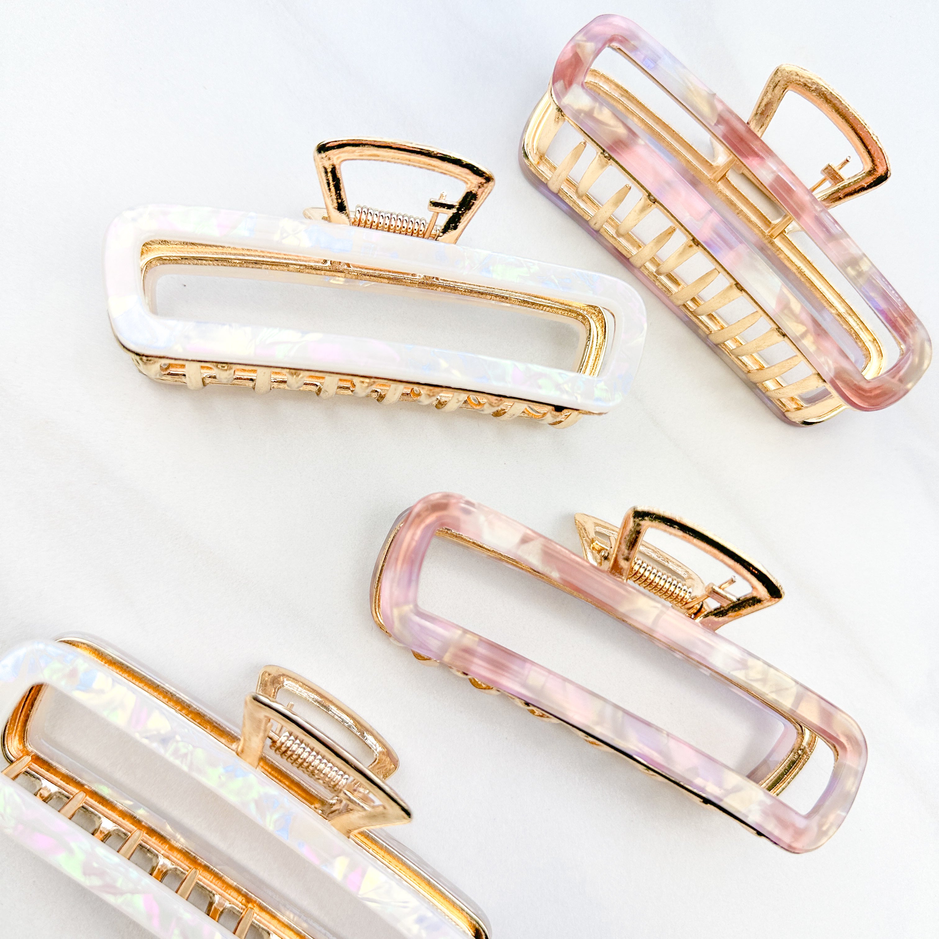 White and pink Break A Leg Clips from The Sarah Wallace Collection, featuring a marble and metal design with a hinge closure.