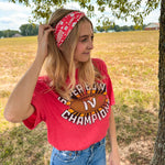Woman smiling in a red Karma Is the Guy on the Chiefs headband, showcasing its versatile, functional design for workouts, long shifts, or playdays.