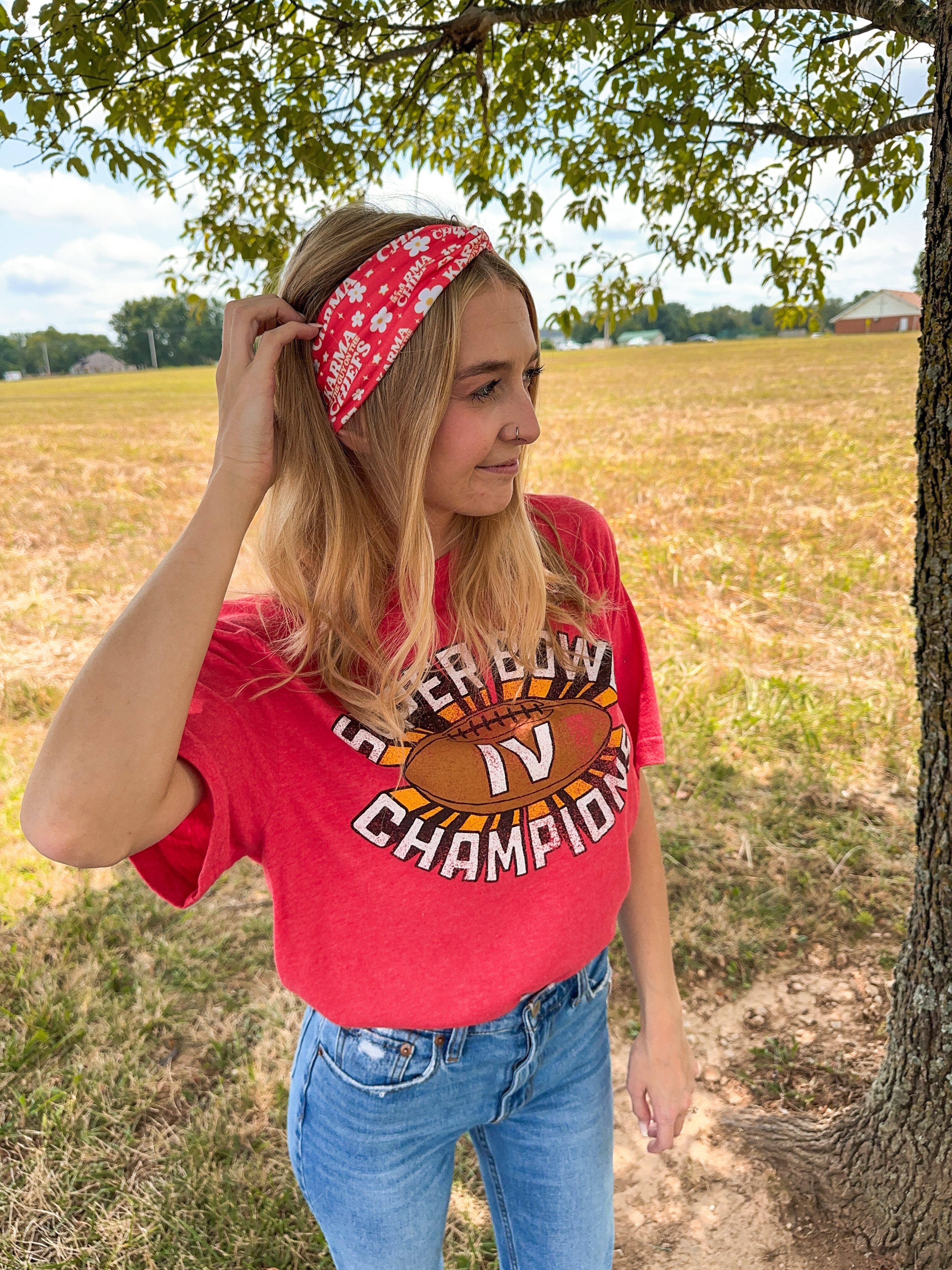 Woman smiling in a red Karma Is the Guy on the Chiefs headband, showcasing its versatile, functional design for workouts, long shifts, or playdays.