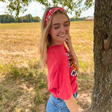 Woman smiling in a red Karma Is the Guy on the Chiefs headband, showcasing its versatile, functional design for workouts, long shifts, or playdays.