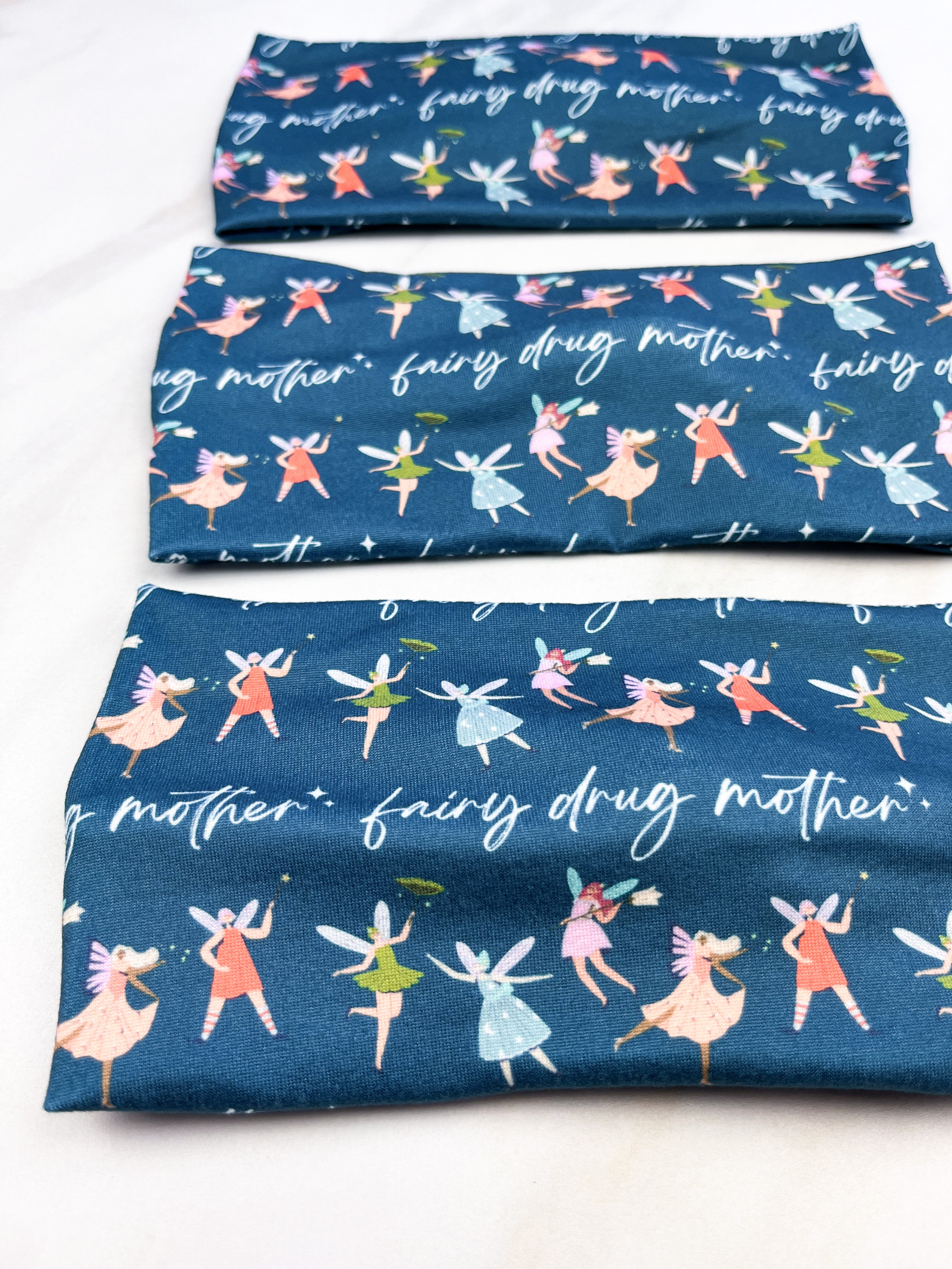 Adult women's navy headband with the script "fairy drug mother" and three small fairy characters across the band