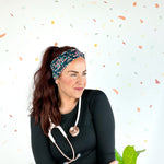 Woman wearing Beautiful Day to Catch Babies Lilac Market Headband with stethoscope, exuding confidence and style.