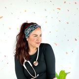 Woman wearing Beautiful Day to Catch Babies Lilac Market Headband with stethoscope, exuding confidence and style.