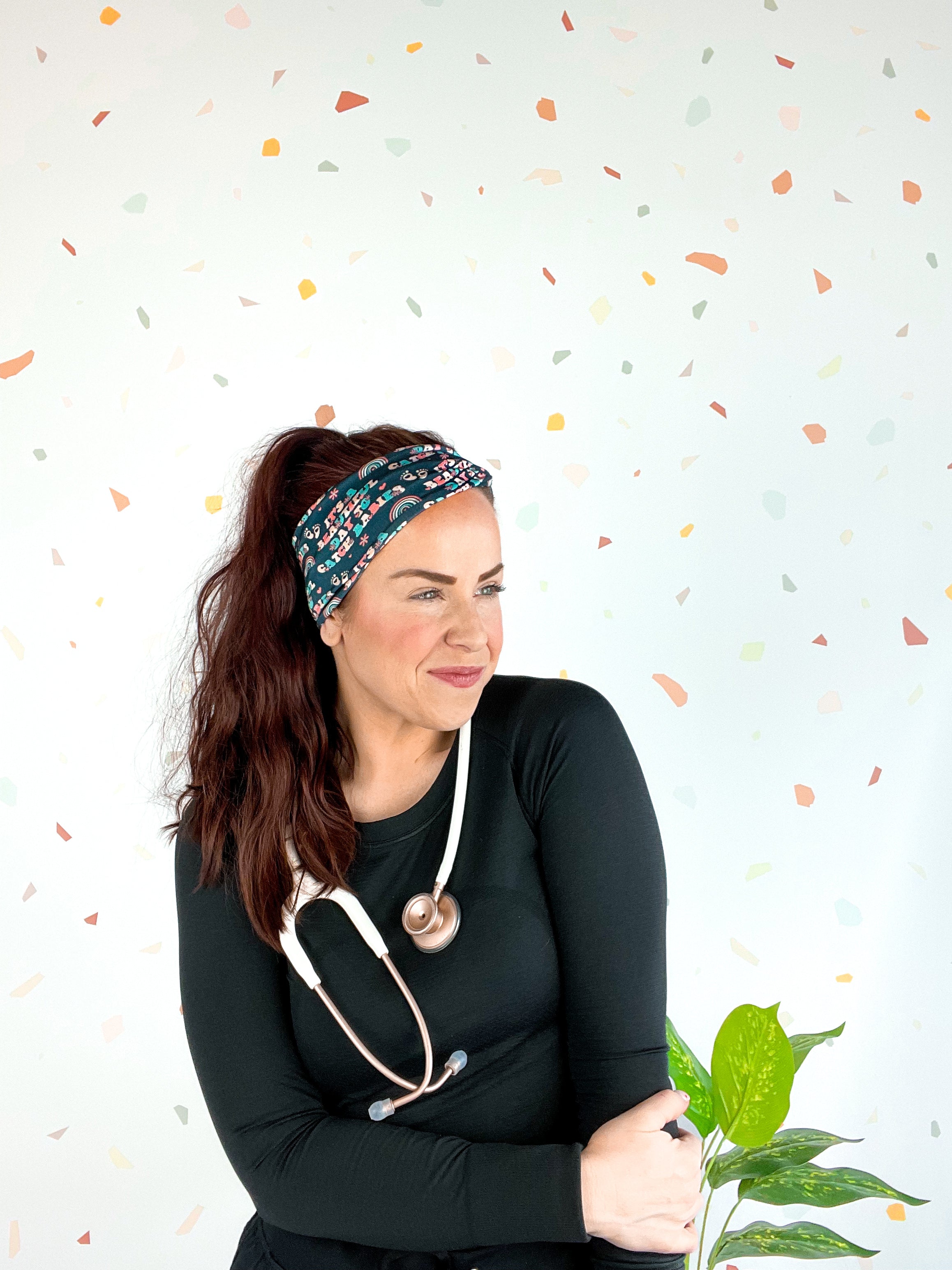 Woman wearing Beautiful Day to Catch Babies Lilac Market Headband with stethoscope, exuding confidence and style.