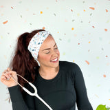 A woman wearing the Ask Me About Our Burritos headband with a stethoscope, smiling.