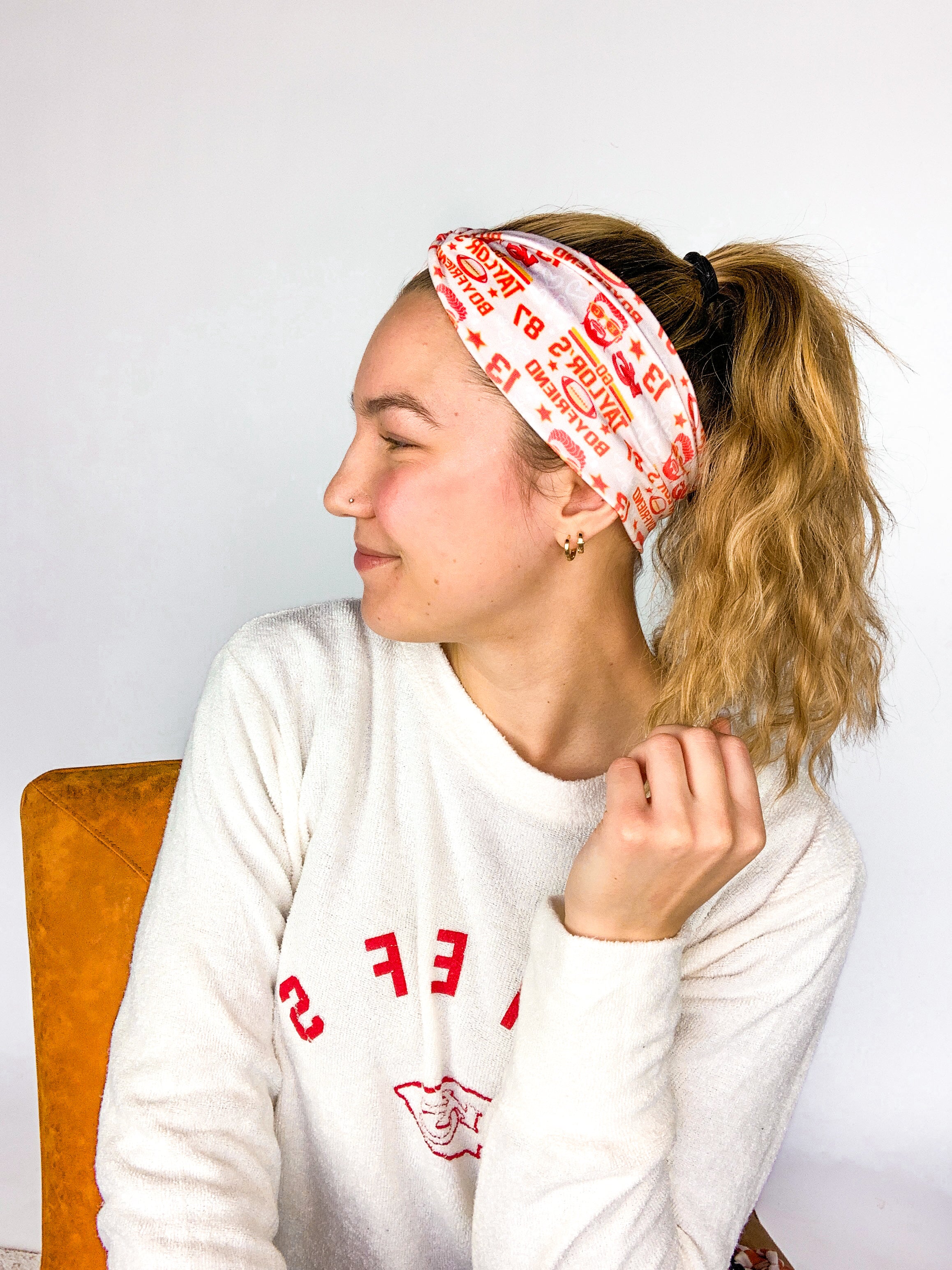 Adult women's grey headband with red and yellow drawings of Travis Kelce, his jersey number, KC Chiefs and hand-drawn hearts that says 'Go Taylor Swift's Boyfriend'