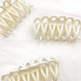 A group of loopy white hair clips, including the Take It Easy Lilac Clip, perfect for all hair types and textures. 4 inches long. Matte material. Hinge closure. Hair-out-of-face approved.