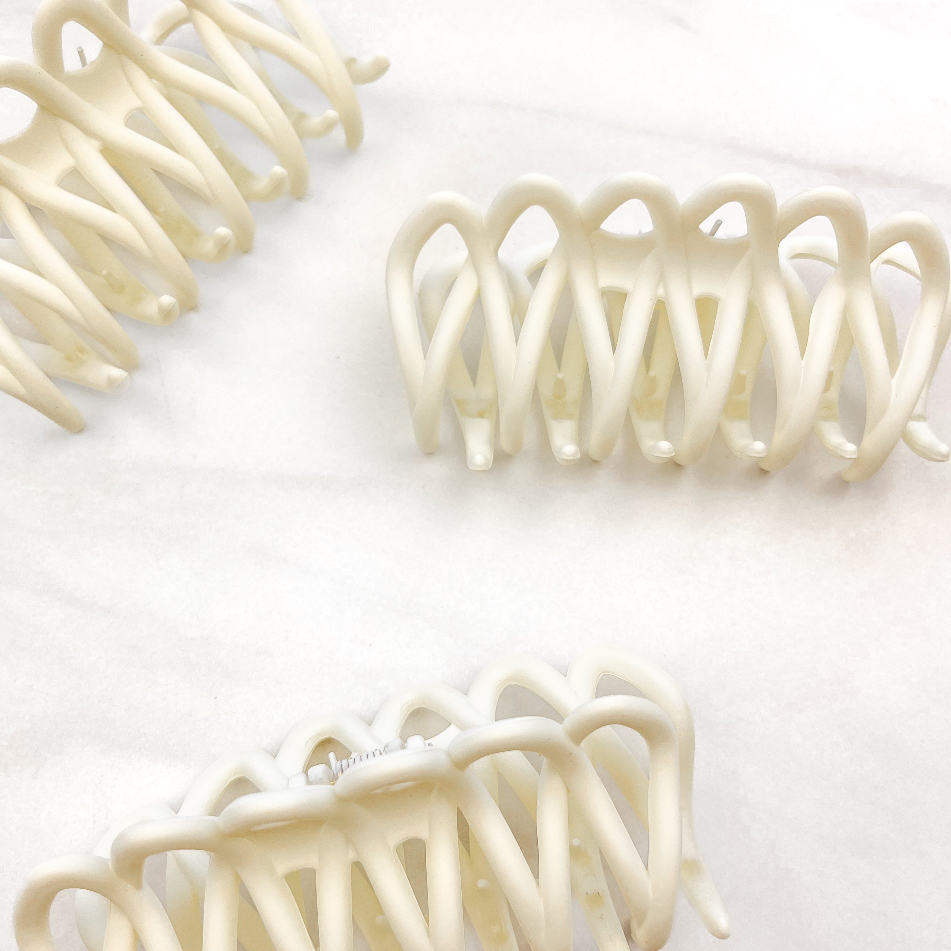 A group of loopy white hair clips, including the Take It Easy Lilac Clip, perfect for all hair types and textures. 4 inches long. Matte material. Hinge closure. Hair-out-of-face approved.