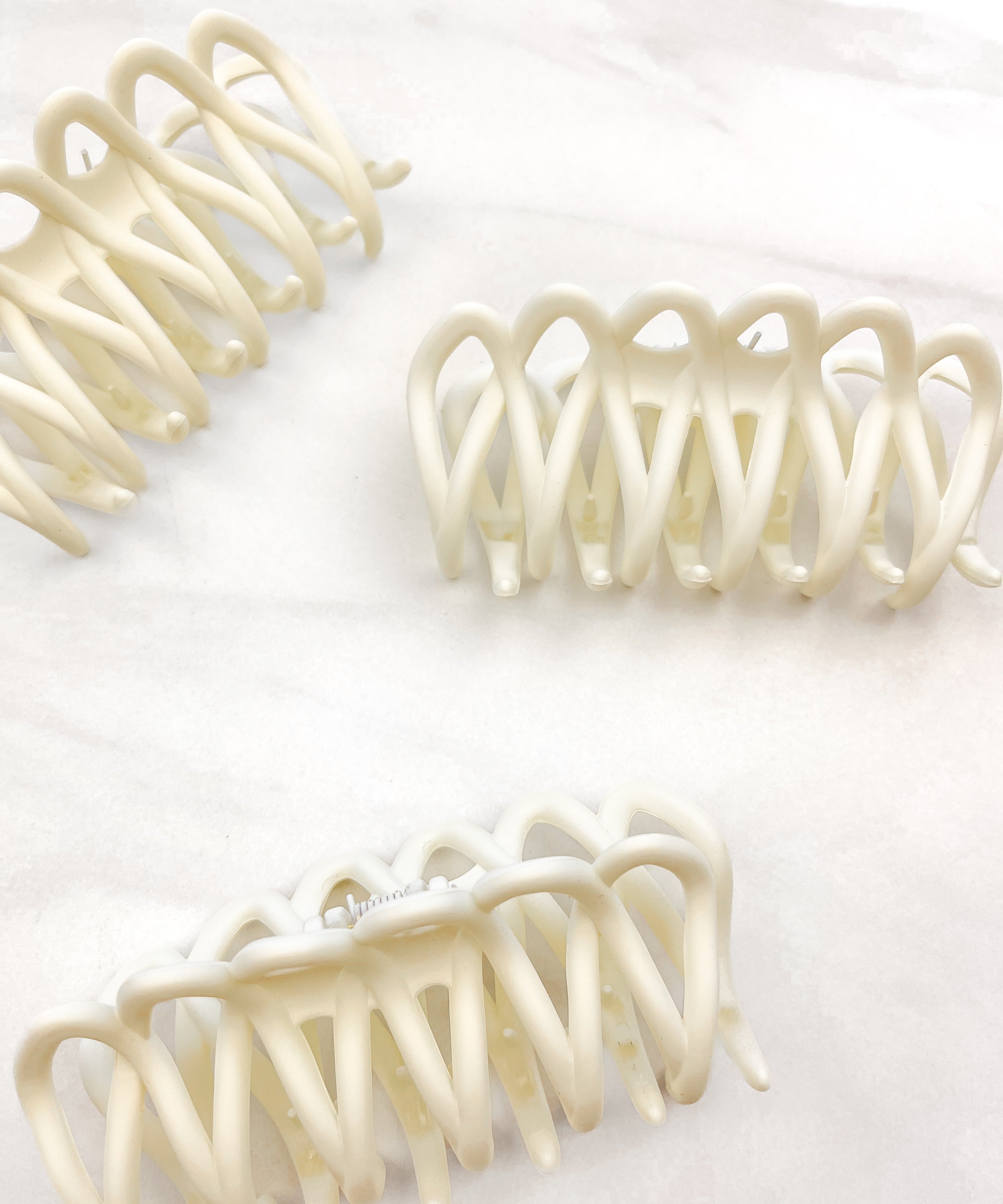 A group of loopy white hair clips, including the Take It Easy Lilac Clip, perfect for all hair types and textures. 4 inches long. Matte material. Hinge closure. Hair-out-of-face approved.