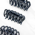 A group of loopy black hair clips, including the Take It Easy Lilac Clip, perfect for all hair types and textures. 4 inches long. Matte material. Hinge closure. Hair-out-of-face approved.