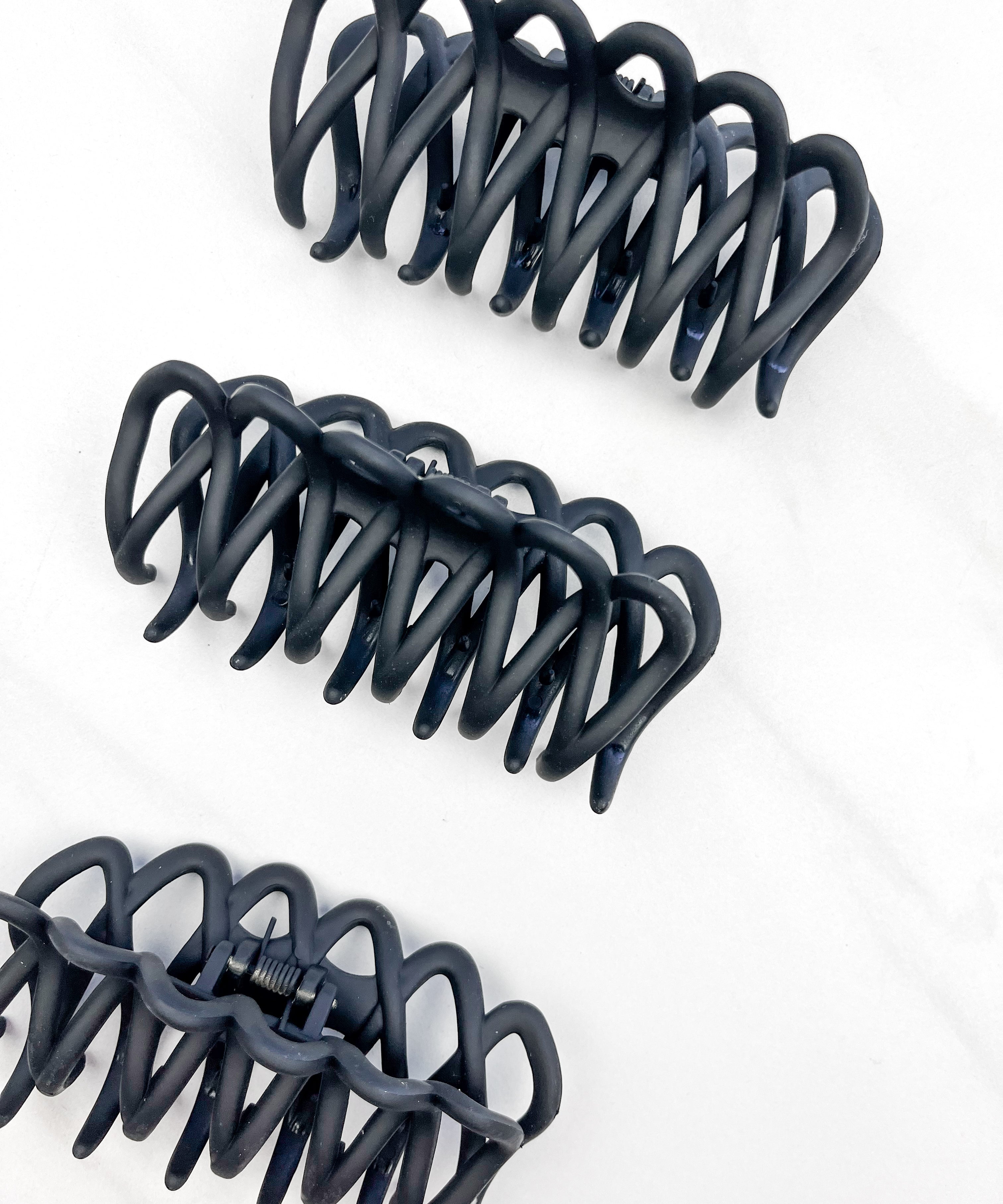 A group of loopy black hair clips, including the Take It Easy Lilac Clip, perfect for all hair types and textures. 4 inches long. Matte material. Hinge closure. Hair-out-of-face approved.