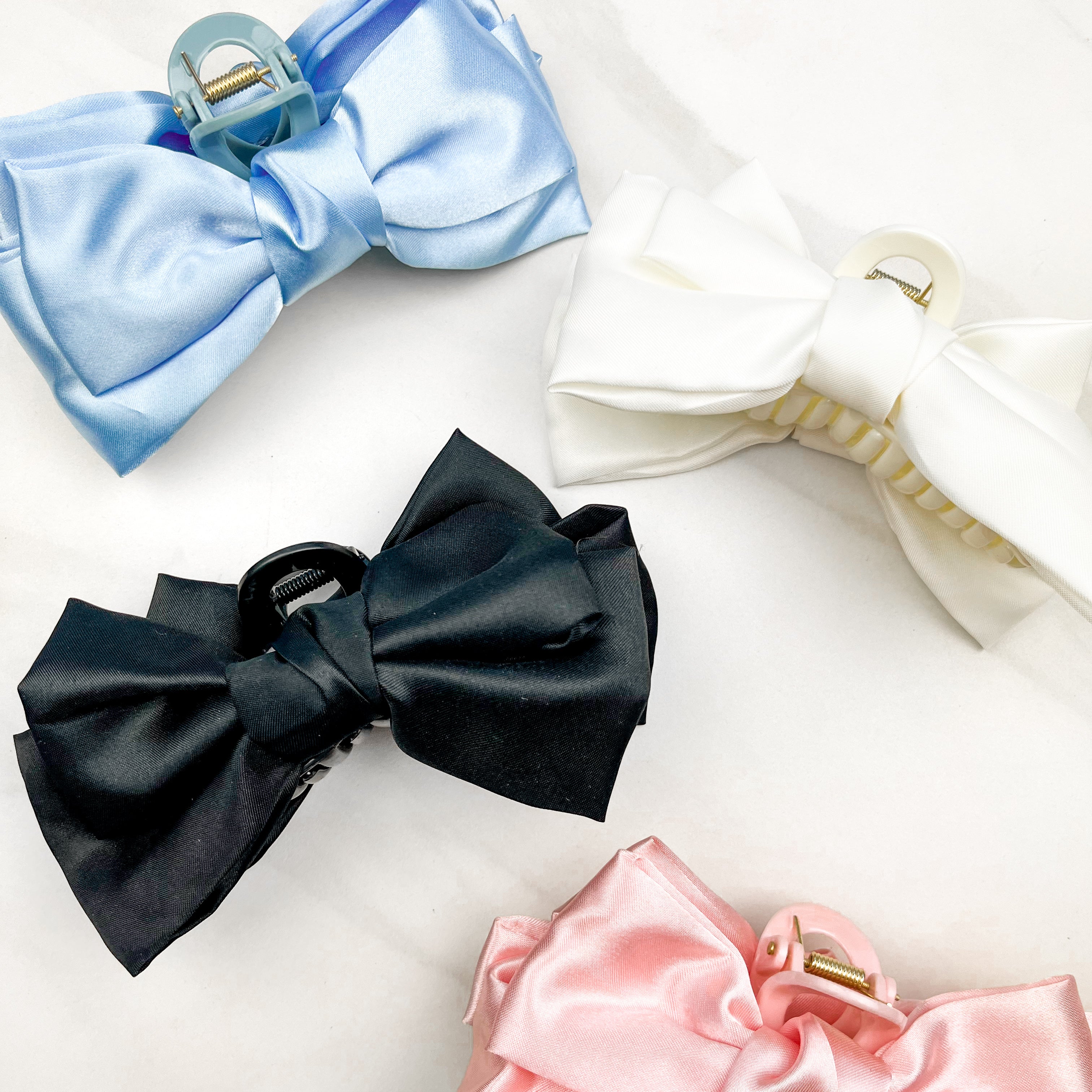 Four of the Classy Chic Lilac Clips, a perfect claw clip for all hair types and textures, made of white, black, pink or blue silky satin material with a hinge closure.