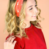  A woman wearing the red and yellow Taylor's Version headband, showcasing the football fashion accessory.