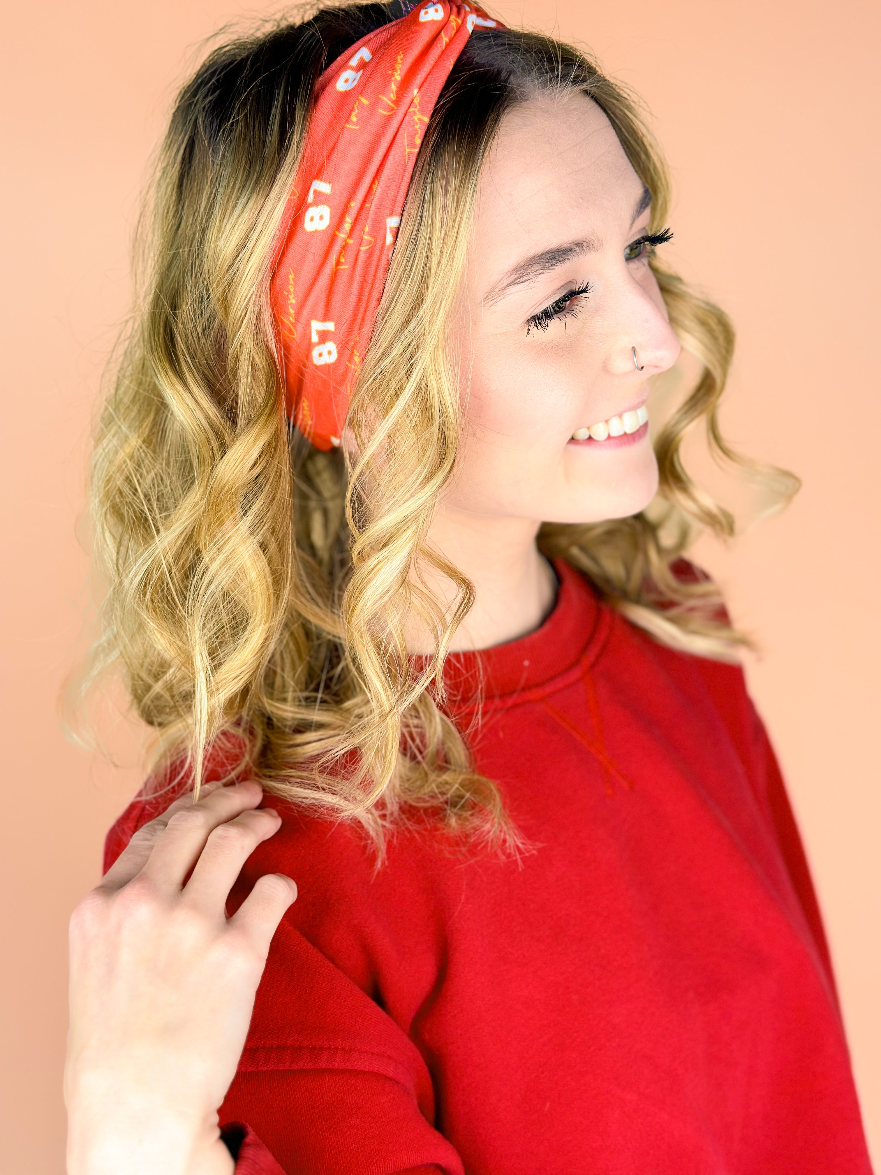  A woman wearing the red and yellow Taylor's Version headband, showcasing the football fashion accessory.
