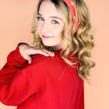  A woman wearing the red and yellow Taylor's Version headband, showcasing the football fashion accessory.
