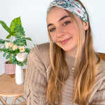 A woman wearing a Lilac Market Brandi Floral on Mint headband, showcasing a white and tan floral print design. Versatile 3-in-1 twist style, sweat absorbent, non-slip, machine washable, designed in Springfield, MO.
