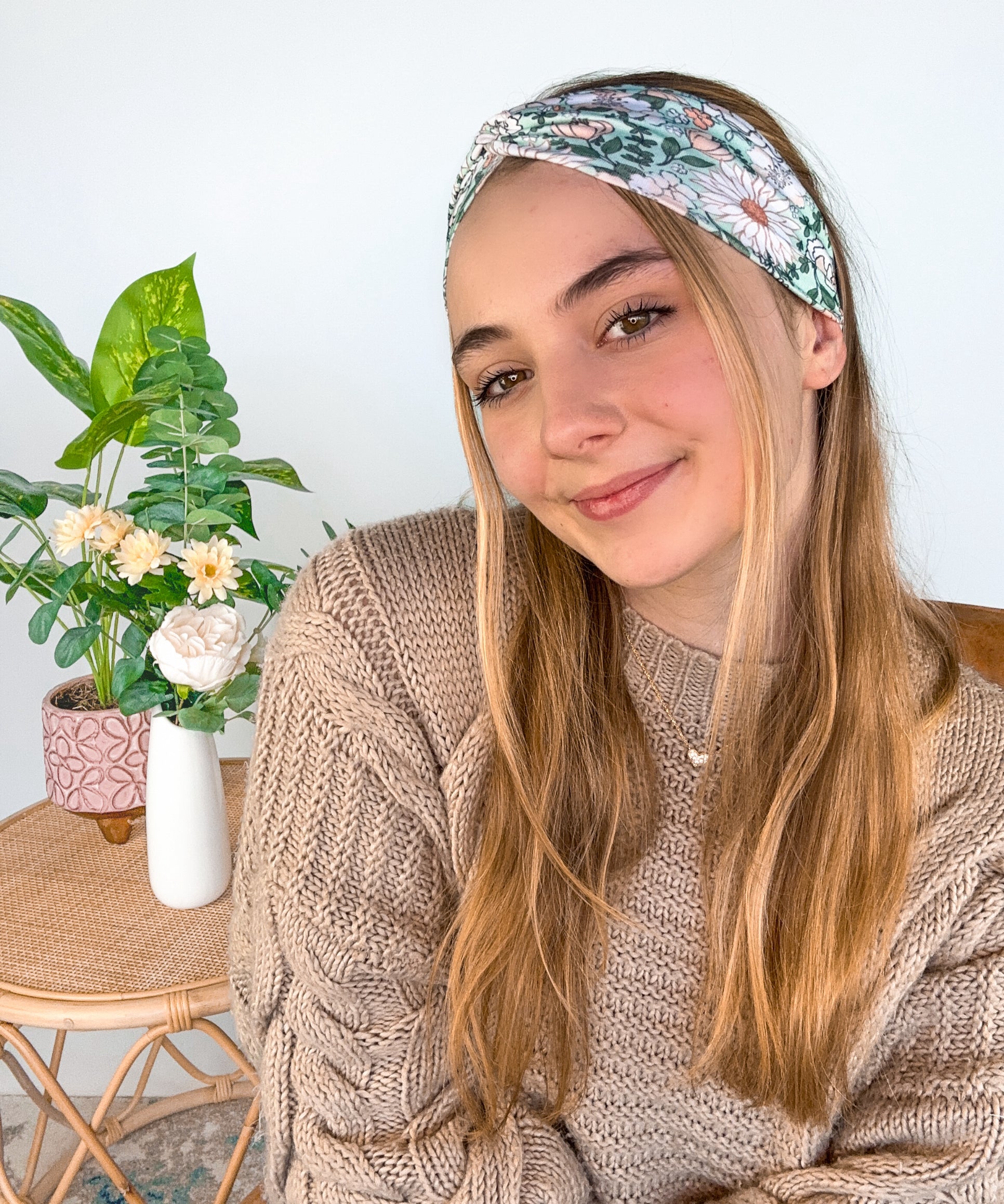 A woman wearing a Lilac Market Brandi Floral on Mint headband, showcasing a white and tan floral print design. Versatile 3-in-1 twist style, sweat absorbent, non-slip, machine washable, designed in Springfield, MO.