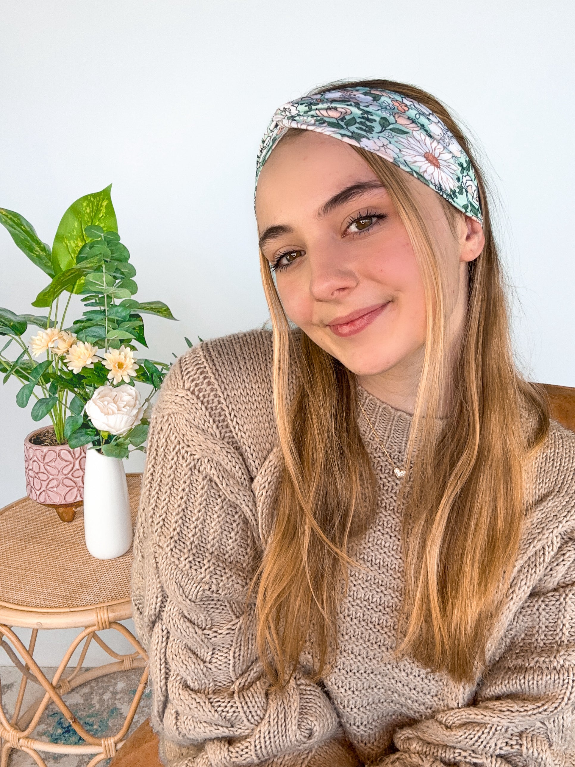 A woman wearing a Lilac Market Brandi Floral on Mint headband, showcasing a white and tan floral print design. Versatile 3-in-1 twist style, sweat absorbent, non-slip, machine washable, designed in Springfield, MO.