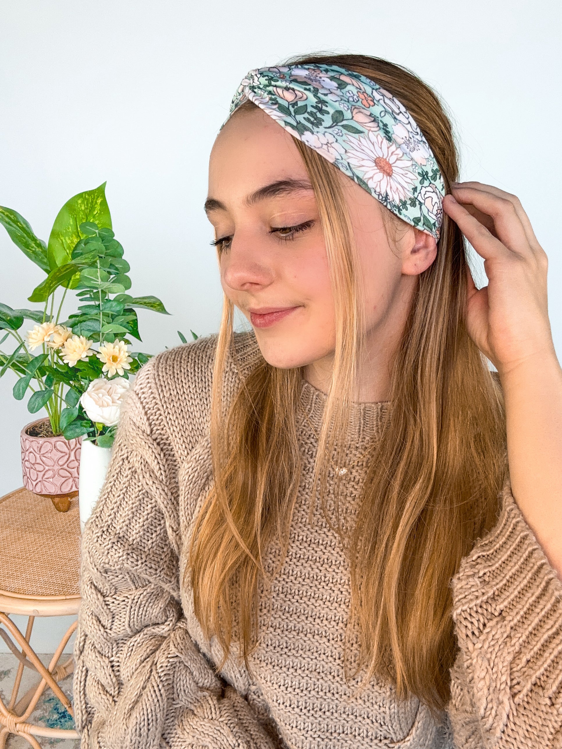 A woman wearing a Lilac Market Brandi Floral on Mint headband, showcasing a white and tan floral print design. Versatile 3-in-1 twist style, sweat absorbent, non-slip, machine washable, designed in Springfield, MO.