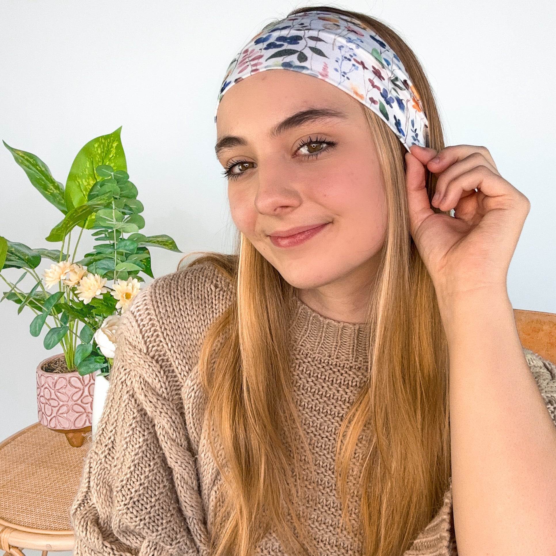 A woman wearing the Alyssa Floral on Ivory headband, showcasing a versatile twist style. Made of soft, stretchy fabric, sweat-absorbent, and non-slip for workouts or play. Designed in Springfield, MO.