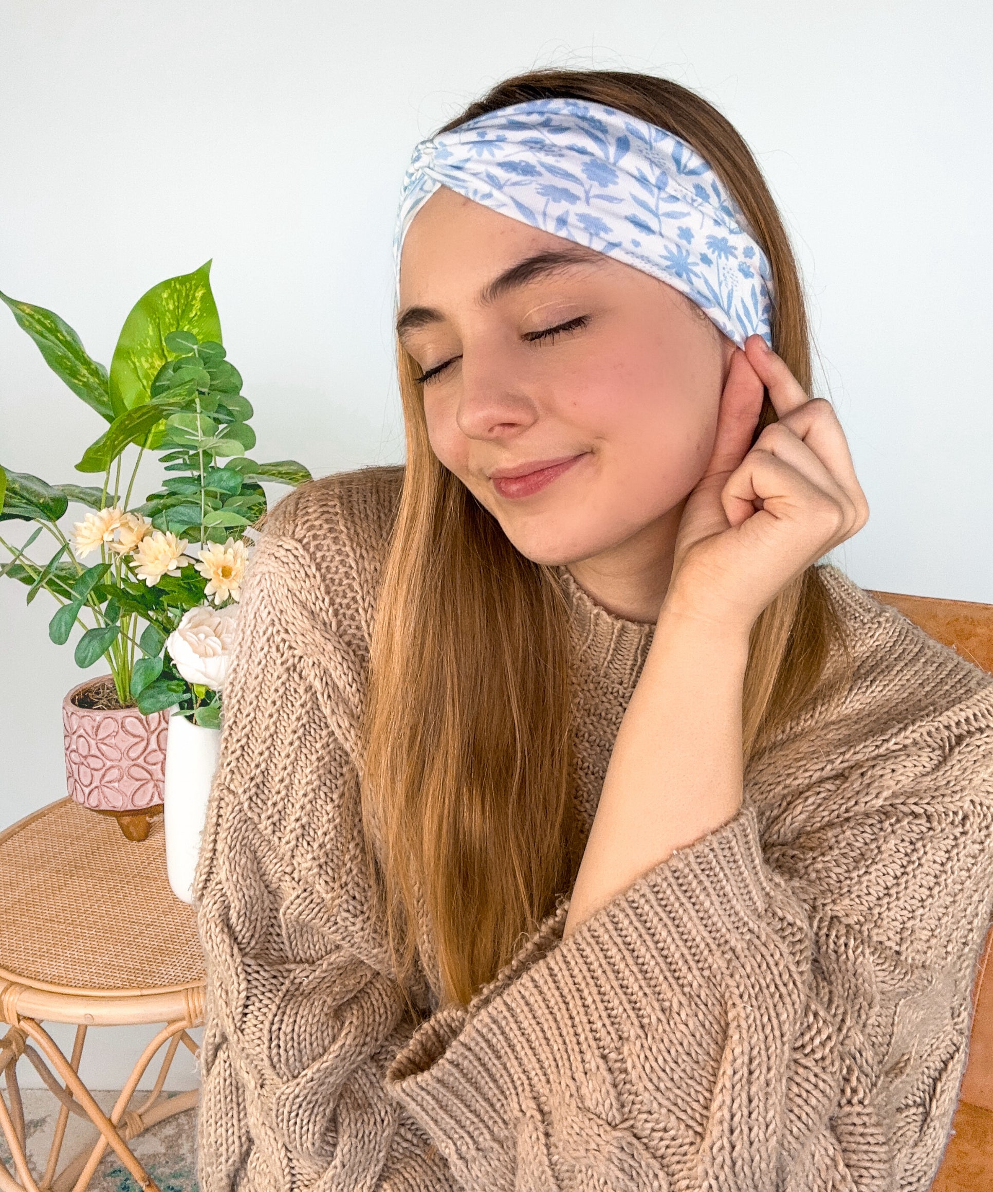 A woman wearing the Olivia Floral on Ivory headband, smiling. Versatile 3-in-1 twist style, machine washable, sweat absorbent, non-slip, designed for confidence and function.