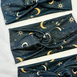 A Dark Side of the Moon headband, showcasing a moon and stars pattern on soft poly-knit fabric. Versatile twist style, sweat-absorbent, and non-slip for workouts or play.