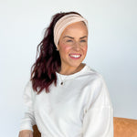 A woman wearing a Chai Latte headband, smiling confidently. Versatile 3-in-1 twist style, sweat absorbent, non-slip, perfect for workouts or play.