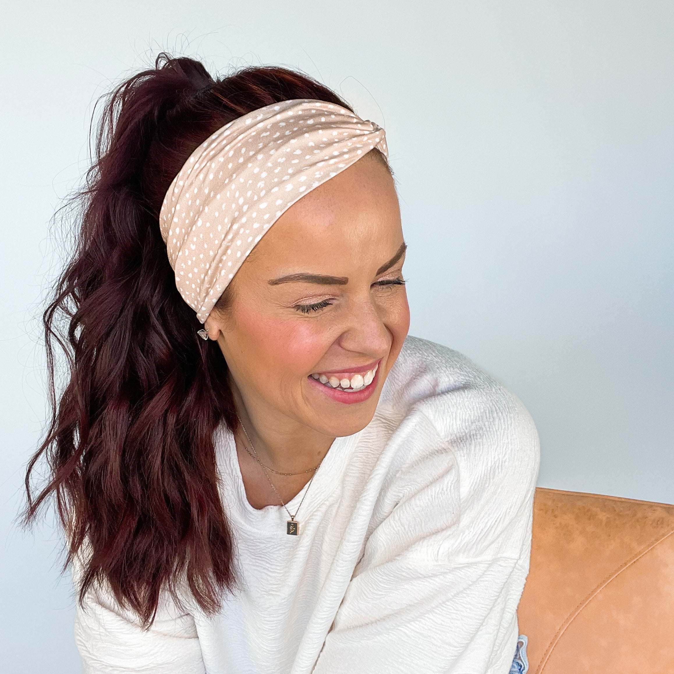 A woman wearing a Chai Latte headband, smiling confidently. Versatile 3-in-1 twist style, sweat absorbent, non-slip, perfect for workouts or play.