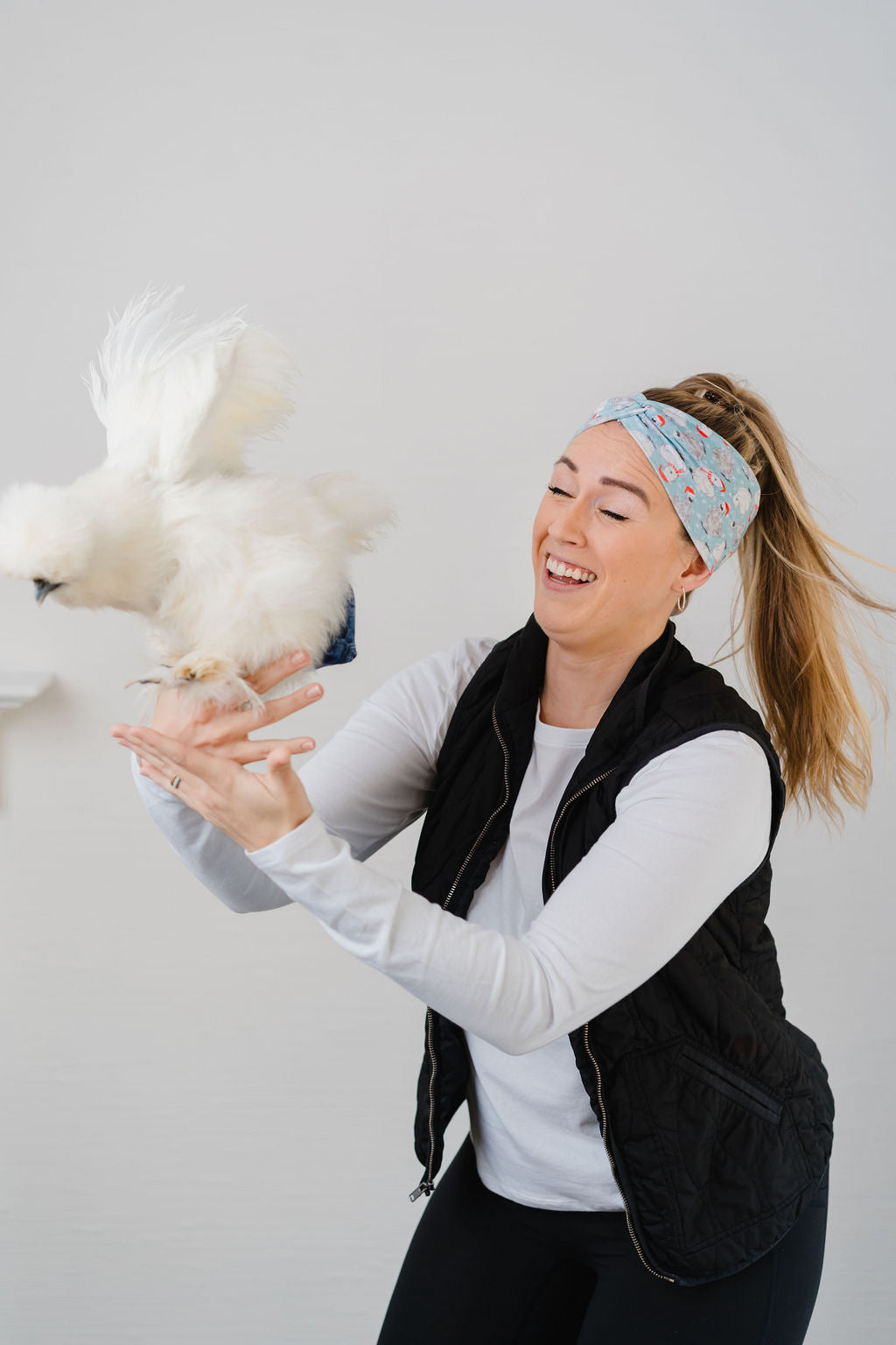 Adult women's light blue headband with white snowflakes and black and white Silkie chickens with red Santa hats and scarves