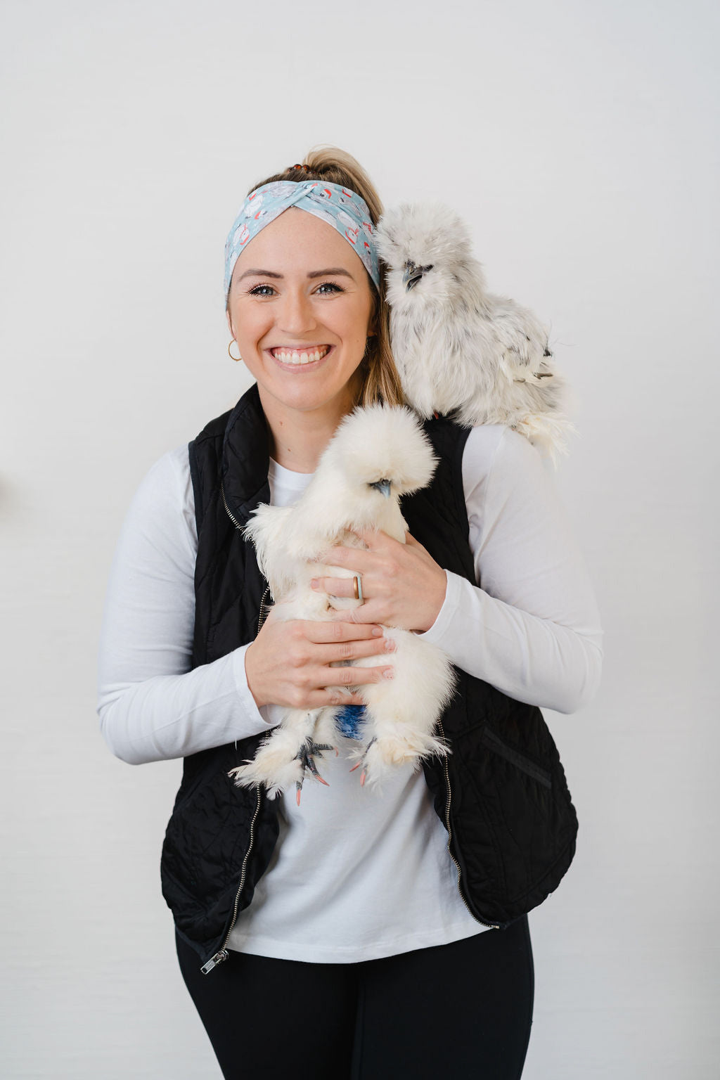 Adult women's light blue headband with white snowflakes and black and white Silkie chickens with red Santa hats and scarves